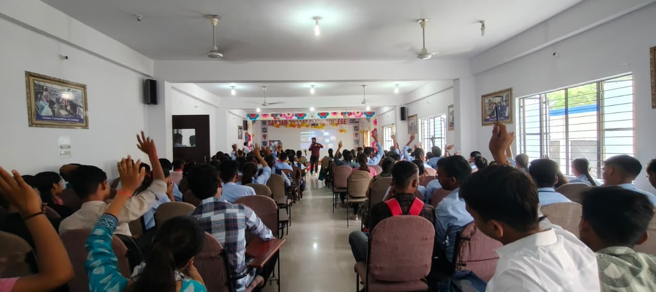 Students raising hands to answer during an AI literacy session in a packed college hall.